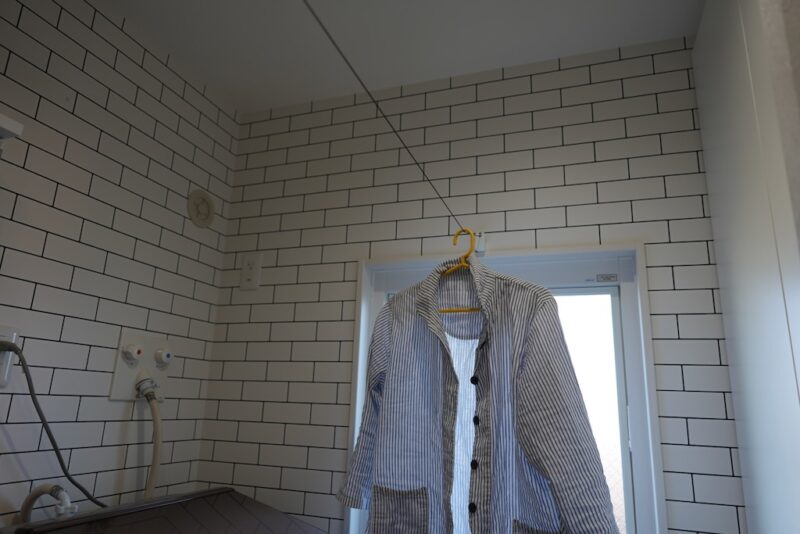 ランドリーロープを壁から引き出し、対面のフックに掛けている様子。ワイヤーは細くて目立たない。