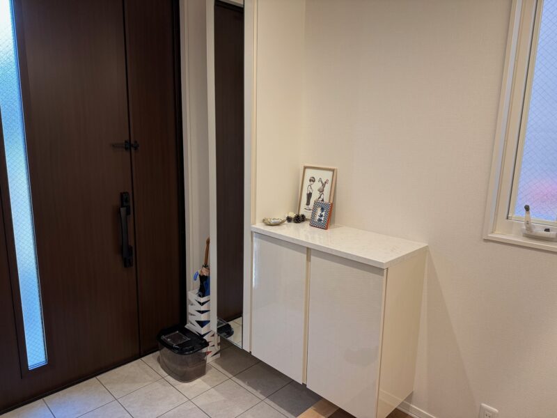 セキスイハイムの玄関。圧迫感のないローカウンター型の下駄箱。上部には雑貨や写真立てが飾られている。