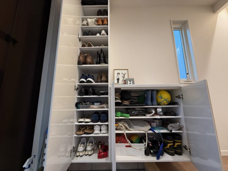 ローカウンター型下駄箱の扉を開けた内部の様子。棚板には家族3人分の靴が隙間なく収納されている。