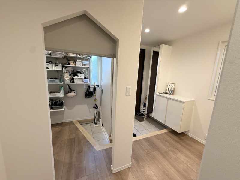 室内廊下から見たシューズクロークの入り口。屋根のような三角垂れ壁のデザインで、目隠し用のロールスクリーンが設置されている。